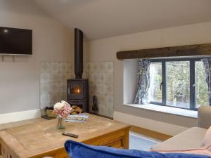 a living room with a wooden table and a wood stove at The Old Shippon At New Ringstones Farm in Mellor
