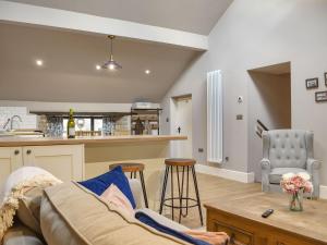 a living room with a couch and a kitchen at The Old Shippon At New Ringstones Farm in Mellor