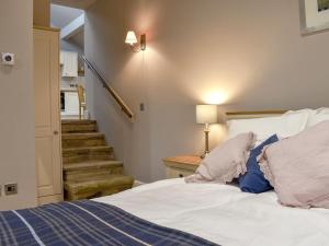 a bedroom with a bed with white sheets and a staircase at The Old Shippon At New Ringstones Farm in Mellor