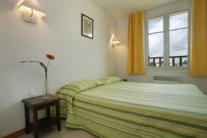 勒韋爾努瓦的住宿－Résidence VTF Les Allées du Green，一间卧室,配有一张床和一个花瓶,桌子上放着鲜花