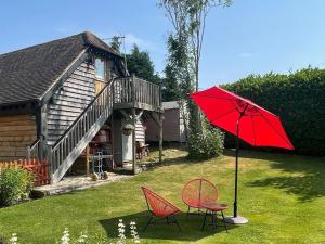 a red umbrella and two chairs in a yard at Loftings in Hendred