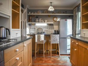 a kitchen with a refrigerator and two bar stools at Woodside in Cloughton