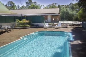 a swimming pool in a yard with chairs and a building at Tocumwal Early Settlers Motel in Tocumwal