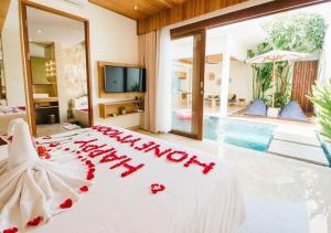 a bedroom with a white bed with a sign that reads happy anniversary at The Mavila - CHSE Certified in Sanur