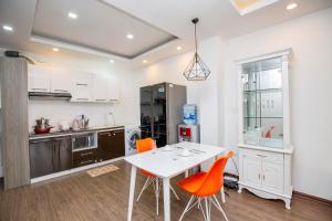 uma cozinha com uma mesa branca e cadeiras laranja em Sumitomo1 serviced apartment & hotel em Hanói