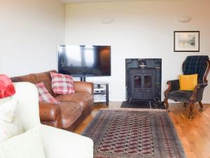 a living room with a couch and a tv at Puddingstone Cottage in Gartmore