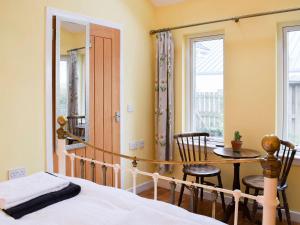 1 dormitorio con cama, mesa y ventana en Puddingstone Cottage en Gartmore