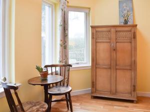 GartmoreにあるPuddingstone Cottageのテーブルと椅子2脚、窓が備わる客室です。
