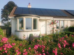 una pequeña casa con paneles solares en el techo en Puddingstone Cottage en Gartmore