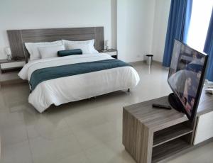 a bedroom with a large bed and a table with a tv at Hotel Altamar Cartagena in Cartagena de Indias