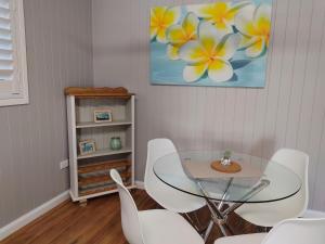 ein Esszimmer mit einem Glastisch und weißen Stühlen in der Unterkunft Cute City Cottage - 2 Bedroom - The Strand in Townsville