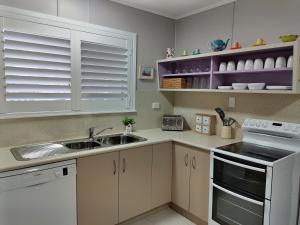 a kitchen with white cabinets and a sink at Cute City Cottage - 2 Bedroom - The Strand in Townsville