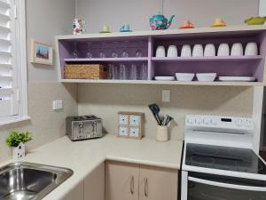 a kitchen with a sink and a stove at Cute City Cottage - 2 Bedroom - The Strand in Townsville