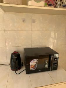 eine Mikrowelle auf einer Theke neben einem Mixer in der Unterkunft CEECEE’S HAVEN in Paulo