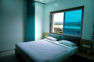 a bed in a room with a large window at Hotel Sai Unity Room in Garudeshwar