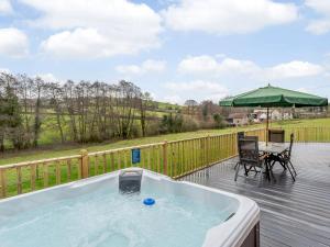 a hot tub on a deck with a table and a chair at Heath Barn in Suckley