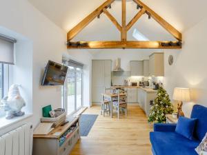 a living room with a blue couch and a kitchen at Heath Barn in Suckley