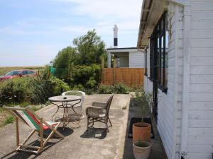 um pátio com uma mesa e cadeiras ao lado de uma casa em Hafod Station em Dungeness