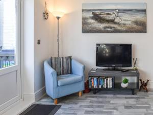 a living room with a blue chair and a tv at La Casita in Herne Bay