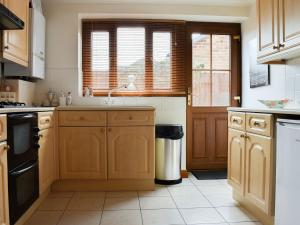 a kitchen with wooden cabinets and a window at Maverhurst in Earnley