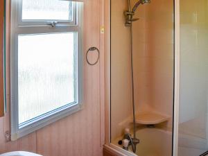 a bathroom with a shower and a toilet and a window at Becleigh-daisy in Bacton