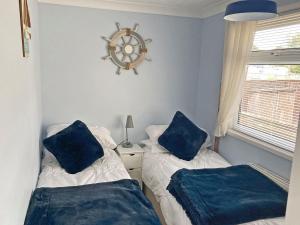 a bedroom with two beds with blue pillows on them at Mistlethrush in Horning