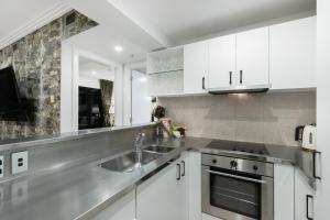 a kitchen with white cabinets and a stainless steel sink at The Celebrity in Auckland
