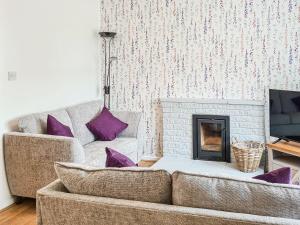 a living room with a couch and a fireplace at 2 Setonhill Cottages in Longniddry