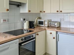 a kitchen with a counter top with a stove and a microwave at 2 Setonhill Cottages in Longniddry