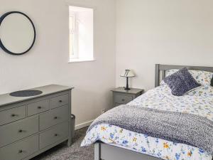 a bedroom with a bed and a mirror and a dresser at 2 Setonhill Cottages in Longniddry