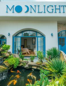 uma pessoa sentada num banco numa casa com um lago de carpas em MOONLIGHT Homestay & Hotel em Pleiku