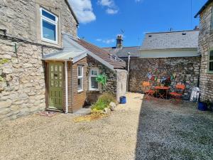 a stone cottage with a green door and a table at The Piggery in Camerton