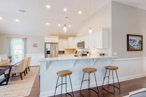 a kitchen with white cabinets and a table and stools at Coastal Serenity - Unit A - Top Floor in Kill Devil Hills