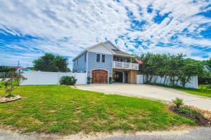 a large blue house with a white fence at Coastal Serenity - Unit A - Top Floor in Kill Devil Hills
