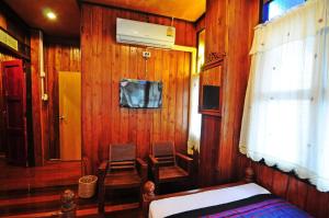a bedroom with a bed and chairs in a wooden wall at Kaloang home in Bangkok +6 photos