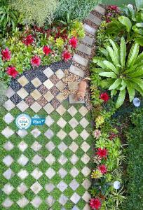 a garden with a checkered walkway with flowers and plants at Ideo Phuket Hotel - SHA Extra Plus in Nai Yang Beach