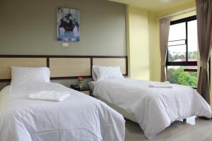a bedroom with two beds with white sheets and a window at Artada Residence in Ban Laem Chabang