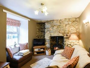 sala de estar con chimenea de piedra y sofá en Glasfor, en Llwyngwril