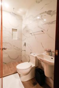 een witte badkamer met een toilet en een wastafel bij Josefina's Tourist Inn in Busuanga