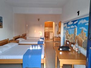 a room with three beds and a table and chairs at ART STUDIO APARTMENTS in Órmos Aiyialís