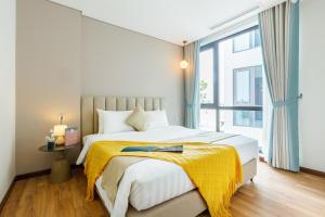 Un dormitorio con una cama con una manta amarilla. en Margaery Boutique Apartment & Skyon9 Rooftop Bar en Hanói