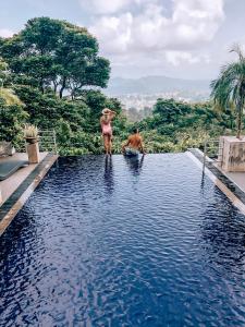 un hombre y una mujer parados en el borde de una piscina en The Theva Residency, en Kandy