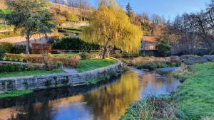 une rivière dans un parc arboré et un pont dans l'établissement Etape du Pont Pinard, à Semur-en-Auxois