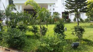 a garden in front of a white building with trees at Paramount Inn in Sriperumbudur