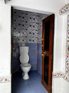 a bathroom with a toilet in a blue room at Wanderlust Hostel & Home Stay in Varanasi