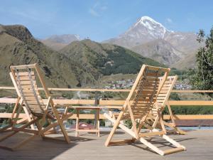卡茲別吉的住宿－Hotel Nestt，山景甲板上配有两把椅子和一张桌子