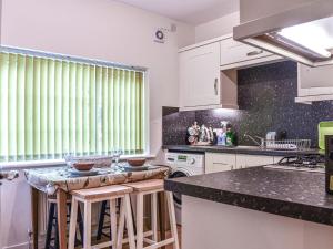 a kitchen with white cabinets and black counter tops at 8 Lowther Gardens in Grange Over Sands
