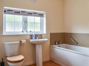 a bathroom with a toilet and a sink and a tub at 8 Lowther Gardens in Grange Over Sands