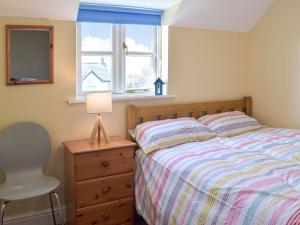 a bedroom with a bed and a dresser and a window at Goslings in Marloes