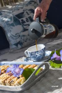 una persona vertiendo café en una taza sobre una mesa en Bollard Bay House, en Knysna
